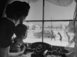 alfred-eisenstaedt-mother-and-child-looking-out-window-as-father-and-older-brothers-walk-to-car-in-snow