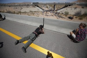 Eric Parker from central Idaho aims his weapon from a bridge as protesters gather by the Bureau of Land Management's base camp