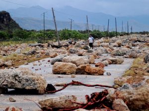 TOPSHOT - A woman walks on October 5, 2016 along a coastal road between Guantanamo and Baracoa which was left covered in rocks and severely damaged after the passage of Hurricane Matthew through the eastern tip of Cuba on Tuesday afternoon. Hurricane Matthew, the Caribbean's worst storm in nearly a decade, barreled towards the Bahamas Wednesday morning after killing nine people and pummeling Haiti and Cuba. / AFP / Yamil LAGE        (Photo credit should read YAMIL LAGE/AFP/Getty Images)